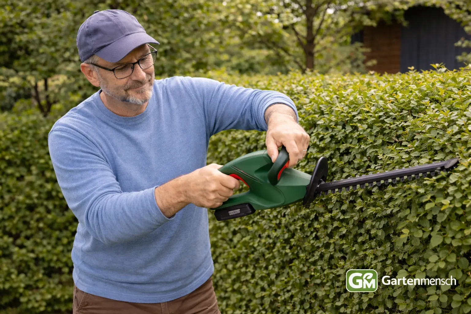 Tobias testet die Bosch EasyHedgeCut 18-45 Akku-Heckenschere beim Schneiden einer Hecke im Garten.